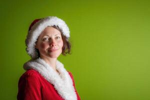 Smiling person in festive red outfit with white fur trim and hat, gazing forward against a plain light green backdrop, emitting a cheerful and festive holiday atmosphere photo