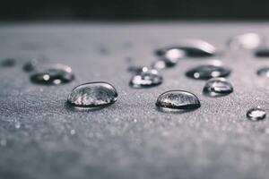 Droplets of water scattered on a smooth, textured surface with a shallow depth of field, focusing on a few droplets in the foreground while others blur into the background photo