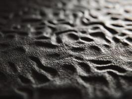 Wavy, textured surface with organic patterns resembling sand dunes in close-up detail. The light casts gently over the ridges, creating shadows and highlights on an uneven terrain photo