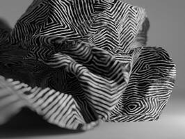 Intricate black and white patterned fabric with geometric, maze-like design folds and undulates, creating abstract textures and shadows, capturing complex shapes and contrasts in detail photo