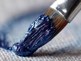 Close-up of a paintbrush with thick, textured blue paint on bristles, spread on a white textured canvas, showcasing artistic detail and creativity in vibrant composition photo