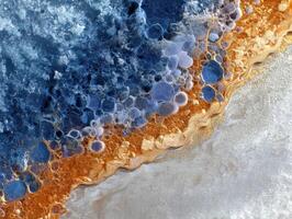 Abstract pattern combining vibrant blue and orange bubble-like formations with a textured gold edge, evoking a natural or cosmic scene. Complex layers and textures merge seamlessly photo