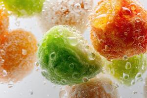 Colorful fruit balls submerged in a fizzy liquid, adorned with bubbles. The vivid hues include green, orange, and yellow, with a glistening texture enhancing the refreshing appearance photo