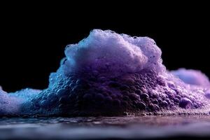 A foamy mound with purple and blue hues, illuminated against a dark backdrop, creates a dramatic, abstract display of texture and contrast in this captivating image of bubbles and light photo