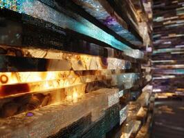 Abstract close-up of illuminated layered stone wall showcasing diverse colors and textures. Warm glowing tones blend with hints of blue, creating an artistic, textured visual experience photo