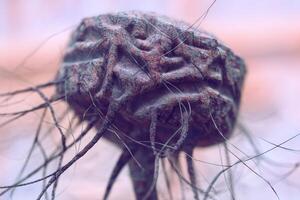 A close-up of an intricate, abstract object with a rough, textured surface. It has a spherical shape with winding details and fine, thread-like strands extending in various directions photo