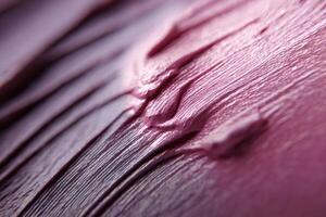 Pink textured surface featuring smooth, wavy patterns with varying shades. The close-up provides an abstract feel, highlighting the rich brush strokes and glossy finish photo