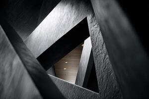 Angular architectural design featuring intersecting gray and black geometric structures creating dynamic triangular shapes with shadows and light accents photo