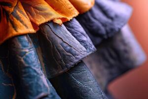 Abstract composition of overlapping textured fabric layers in deep blues and vibrant oranges, creating a dynamic visual contrast with intricate folds and detailed stitching patterns photo
