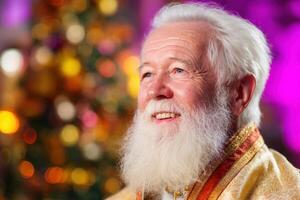 An elderly man with a white beard, dressed in festive attire, smiles warmly against a backdrop of colorful, blurred lights suggesting a joyful, celebratory atmosphere photo