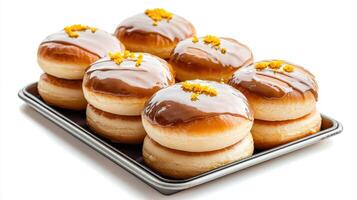 A tray of donuts with orange icing on top photo