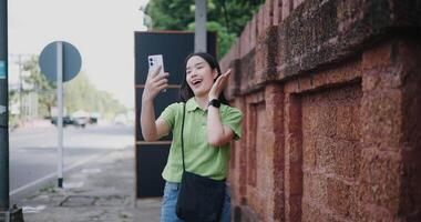 Handheld shot, Cheerful young woman happily takes a selfie while walking along a sidewalk video