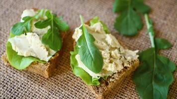 Homemade rye bread with herring paste and arugula on a burlap tablecloth video