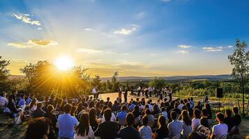 A group of people sitting on a hillside at sunset photo