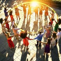 Group of people dancing in circle with sun shining through photo