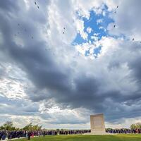 A crowd of people standing around a monument in the grass photo