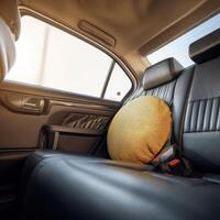 A yellow pillow sits on the back seat of a car photo