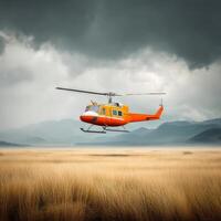 An orange helicopter flying over a field with mountains in the background photo
