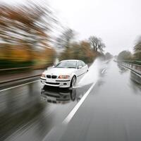 A white bmw driving on a wet road photo