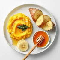 A plate with a bowl of mashed potatoes, bananas and honey photo