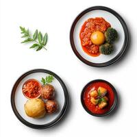Three plates with food on them, including a meatball, a vegetable and a tomato photo