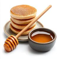 Stack of pancakes with honey and wooden spoon on white background photo