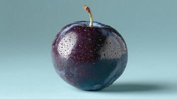 A juicy, ripe plum with water droplets on a blue background. photo