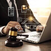 Real Estate Law Concept Judge with Gavel Reviews Property Records Online on Laptop for Legal Judgement. photo
