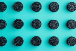 An array of black sandwich cookies is arranged neatly on a light blue surface photo