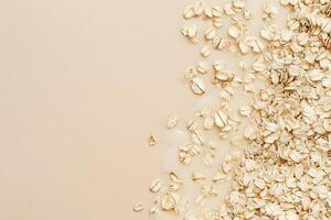 Beige background shows a portion of dry oatmeal alongside liquid oats, spilling across it photo