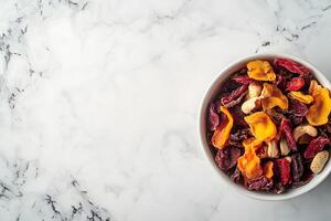 Bowl of mixed dried apricots, fruits, and nuts displayed on a marbled white surface photo