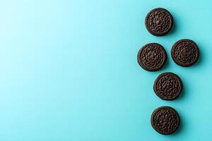 Five dark chocolate cookies arranged in vertical row against turquoise background create a playful vibe photo
