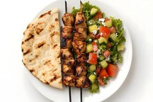 Flatbread, chicken kebab skewers, and mixed salad are displayed on a white plate, ready to eat photo