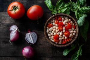 Fresh tomatoes and red onions rest alongside creamy beans and basil on a dark surface photo