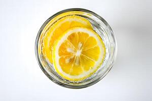 From above, lemon slices float in glass of sparkling clear water on a white background photo