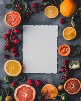 Halved vibrant citrus fruits, raspberries, berries, and leaves frame a central blank paper elegantly photo