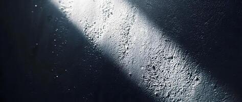 Light illuminates the textured surface of a dark wall creating a unique contrast photo