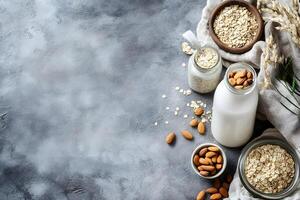 Overhead shot presents nutritious almond milk with oats in jars and bowls on gray texture photo