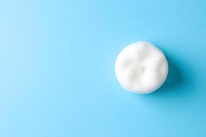 Overhead view captures a single circular white soap foam against a serene blue background photo