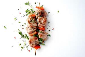 Roasted meat kebab skewer served with bell pepper and rosemary rests on white backdrop photo