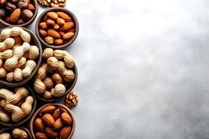 Rustic wooden bowls filled with assorted mixed nuts sit arranged on gray textured backdrop photo