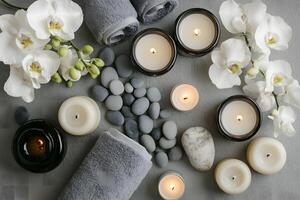 Serene spa arrangement displays soft white orchids, smooth gray stones, lit candles, and folded towels photo