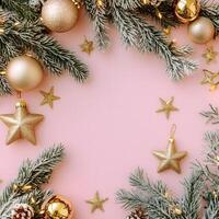 Snow dusted pine boughs form a frame with gold ornaments against a pink background photo
