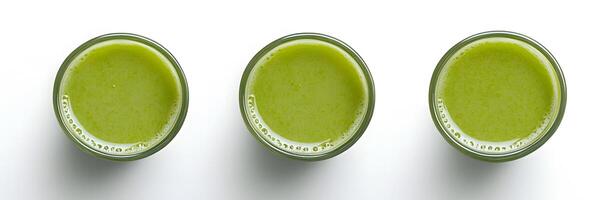 Three transparent glasses are filled with green smoothie, set against a bright white backdrop photo
