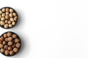 Two bowls hold walnuts and groundnuts, displayed against a pristine, bright white backdrop photo