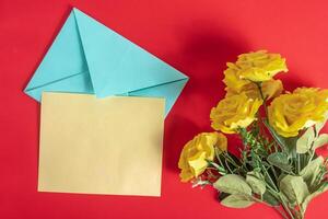 Yellow flowers with envelope and blank card on red background for celebration message. Top view. photo
