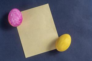Colorful Easter eggs and plain yellow paper on a dark background. photo