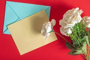 Festive card and white roses on a vibrant red background. Top view photo