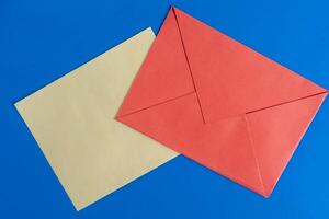 Bright red envelope with paper on a blue background surface. photo