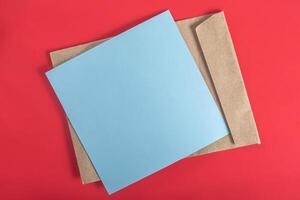 Blue paper sheet and brown envelope on a red background. photo